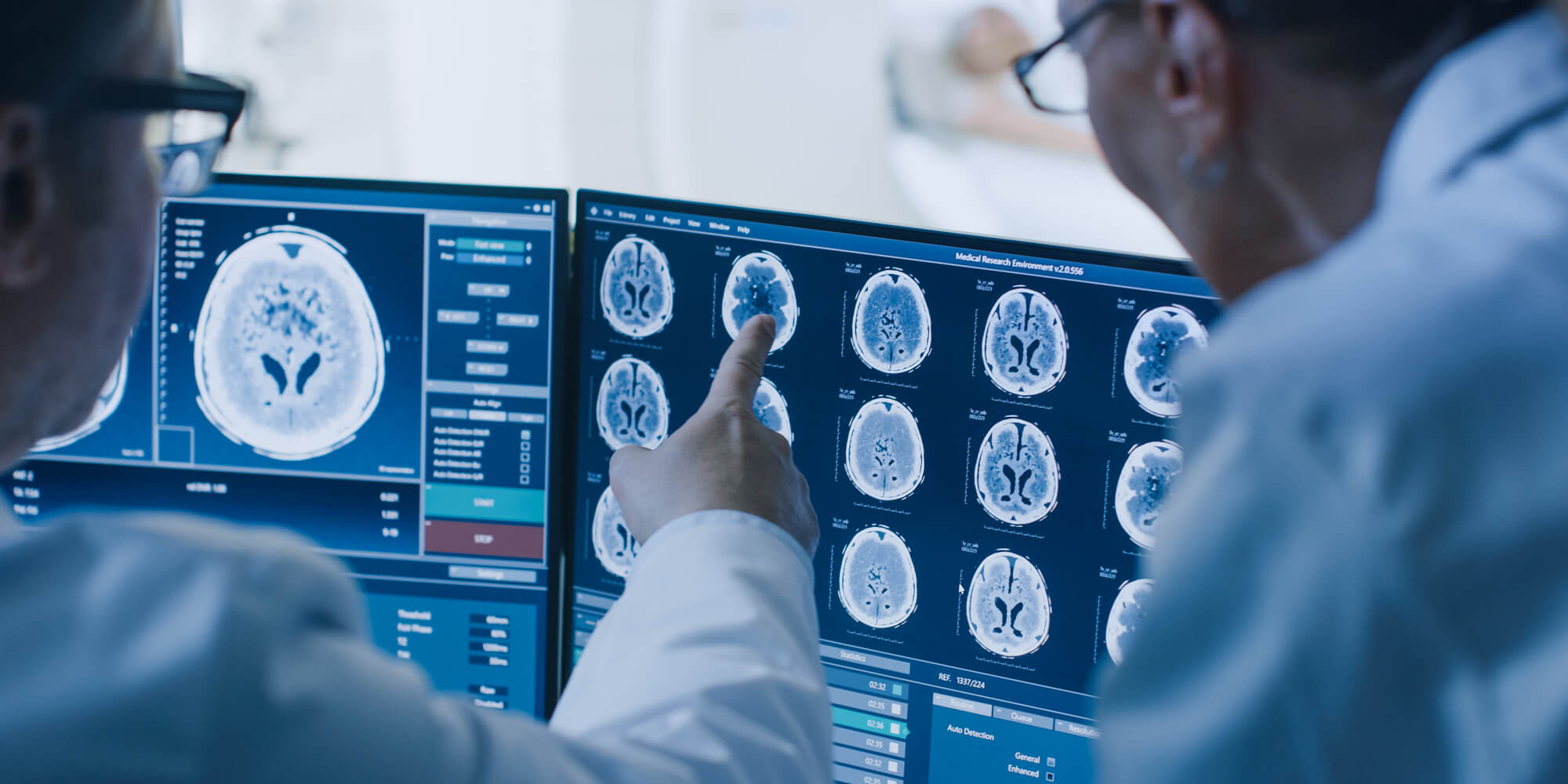 Two doctors pointing to screen with medical scan results