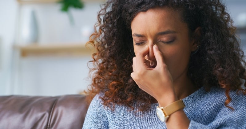 Woman experiencing sinus symptoms, pinching her nose