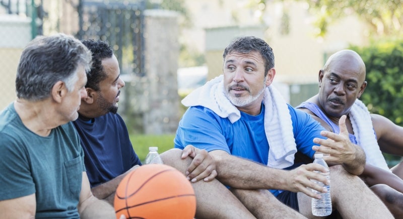 Men playing basketball while talking about urinary incontinence