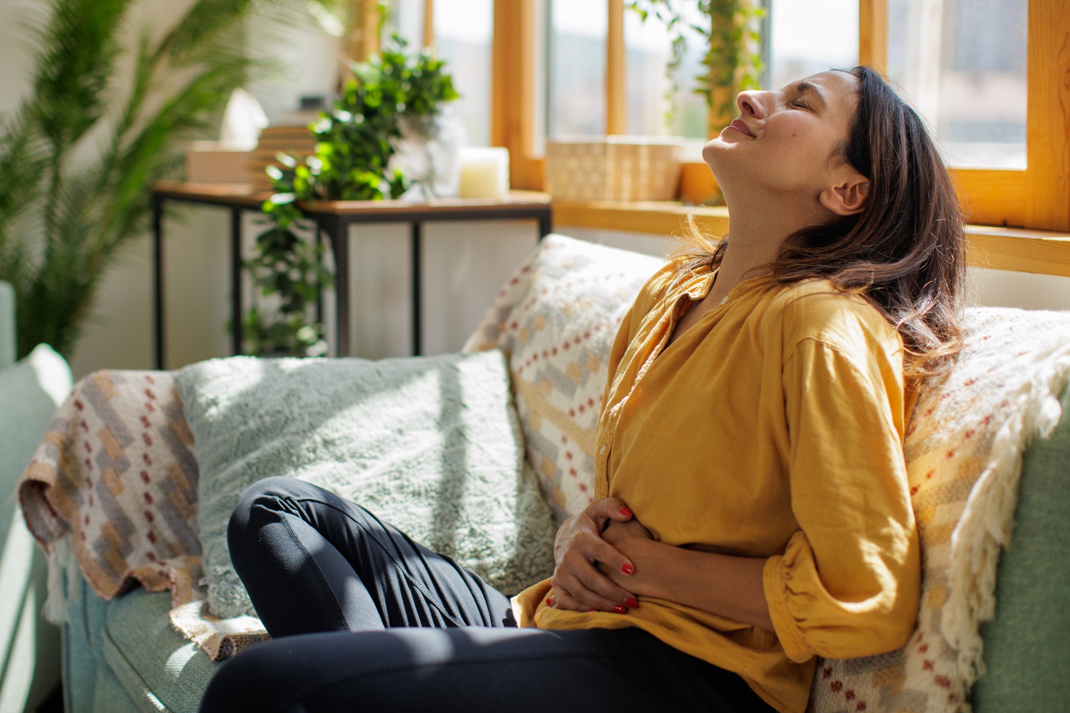 Women sitting on couch experiencing uterine fibroid-related pain