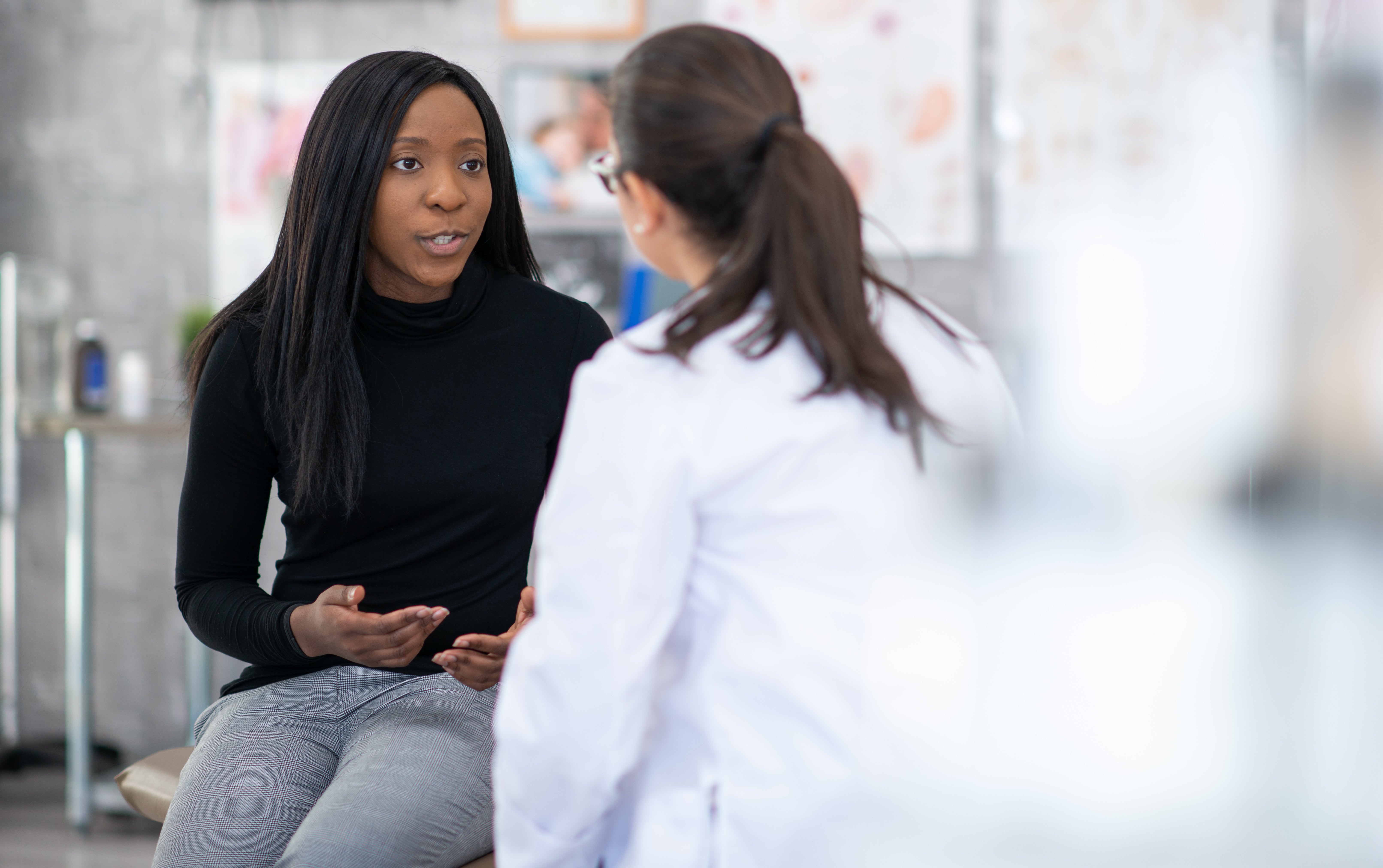 Woman sitting in discomfort as her doctor discusses pelvic prolapse with her