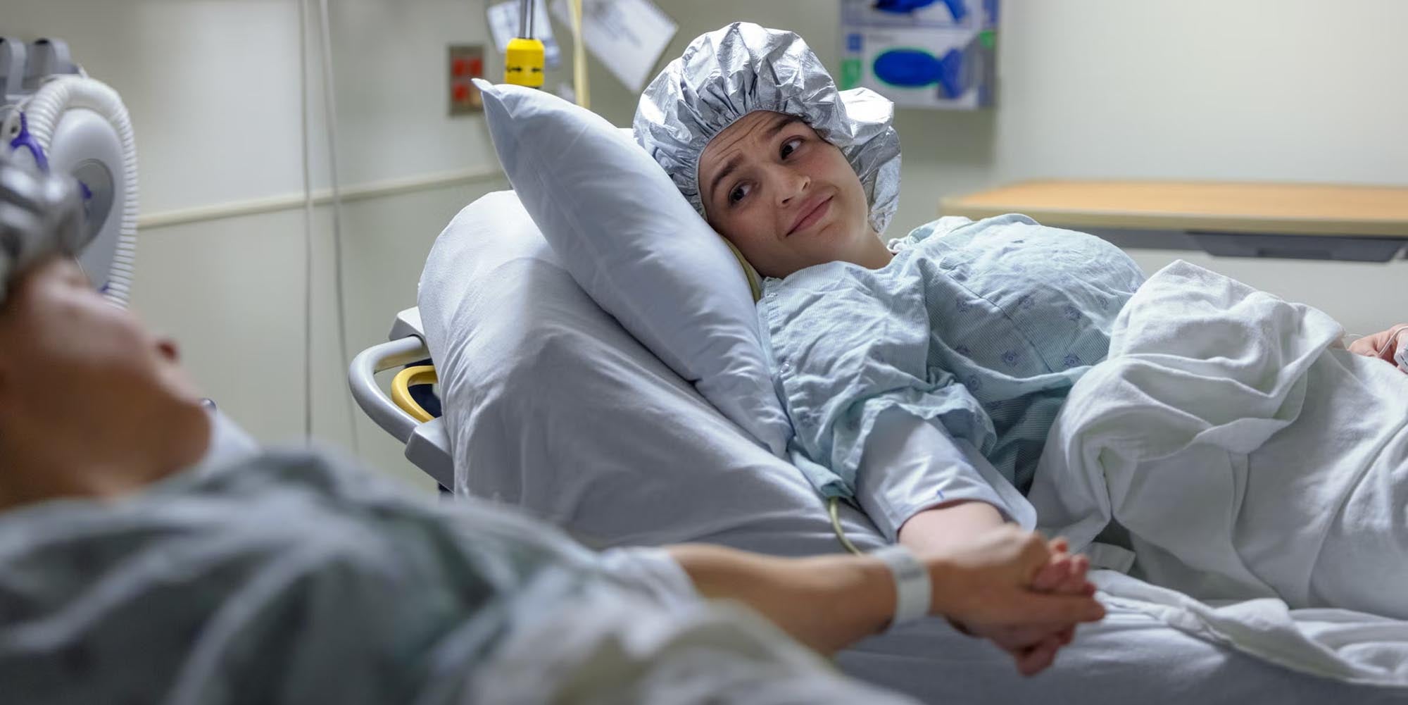 Two patients in a hospital holding hands