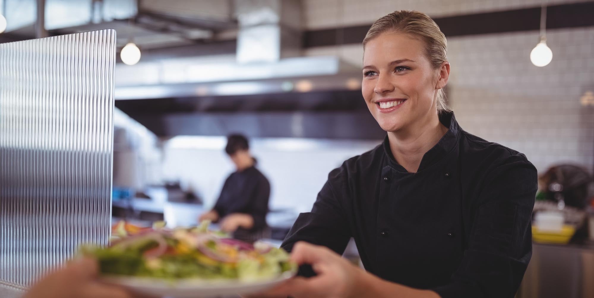Restaurant worker handing off a plate of food