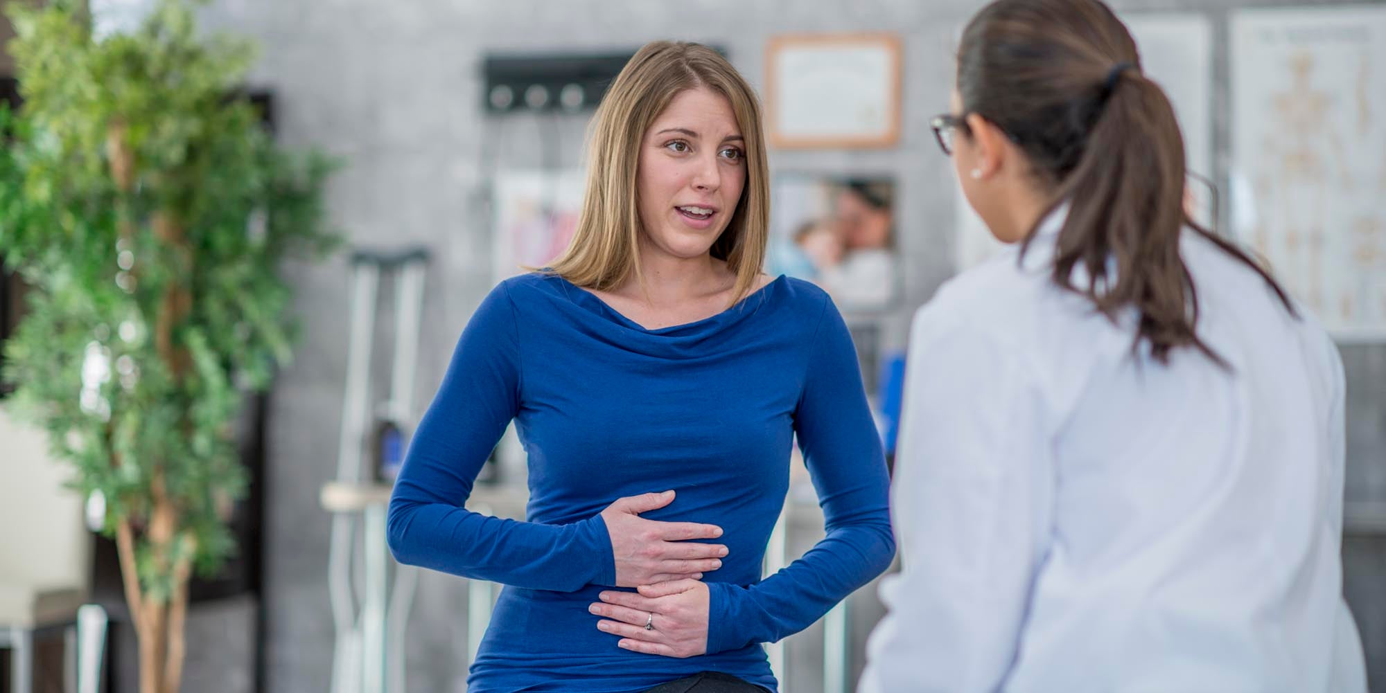 Patient holding her stomach talking to a provider