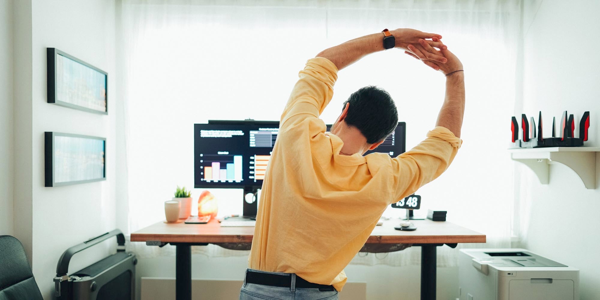 Man standing and stretching in front of computer